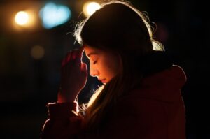 girl praying by candle light